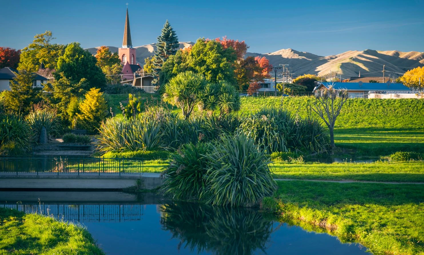 A stream, greenery, and a church in a Blenheim landscape