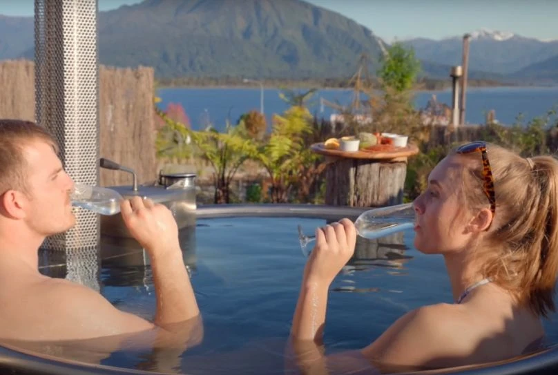 Couple enjoying a glass of wine in the Lake Brunner Hotel cedar hot tub