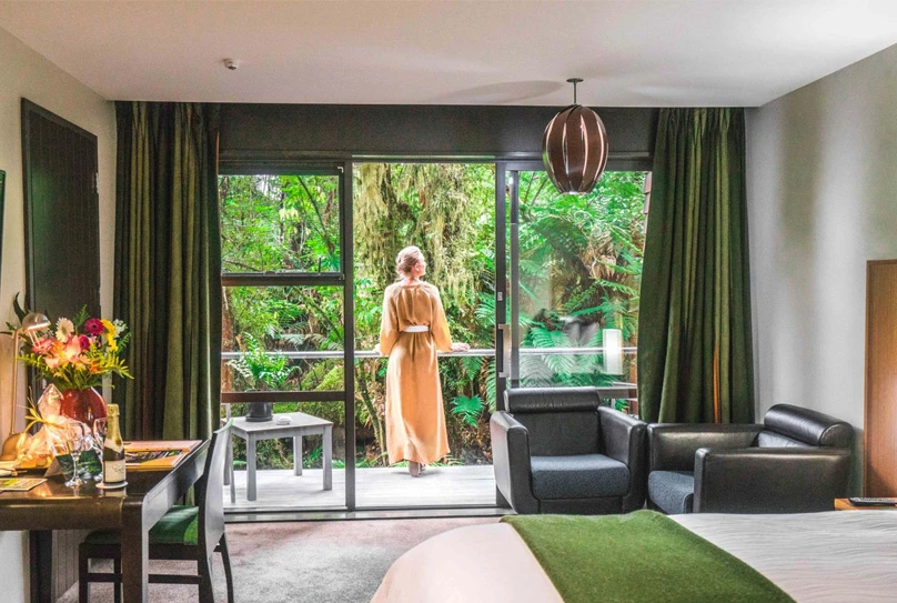 Woman enjoying balcony in Te Waonui Forest Retreat suite