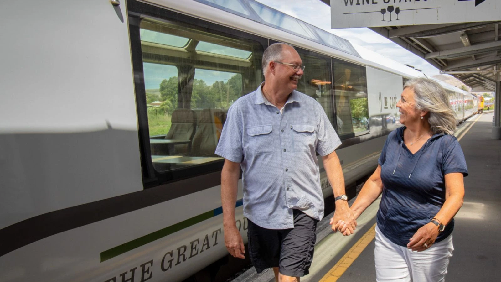 Couple walking hand-in-hand alongside the coastal pacific train