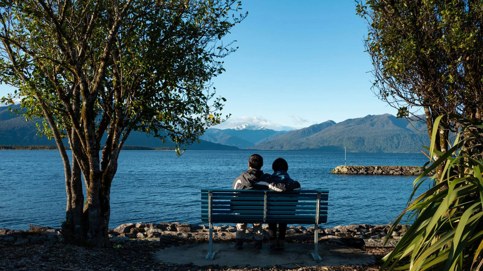 Couple sitting on bench overlooking Lake Brunner