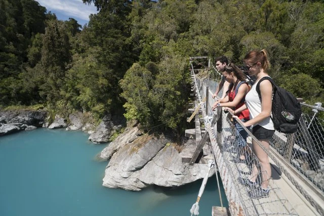 Group of people looking over the swing bridge at Hokitika Gorge