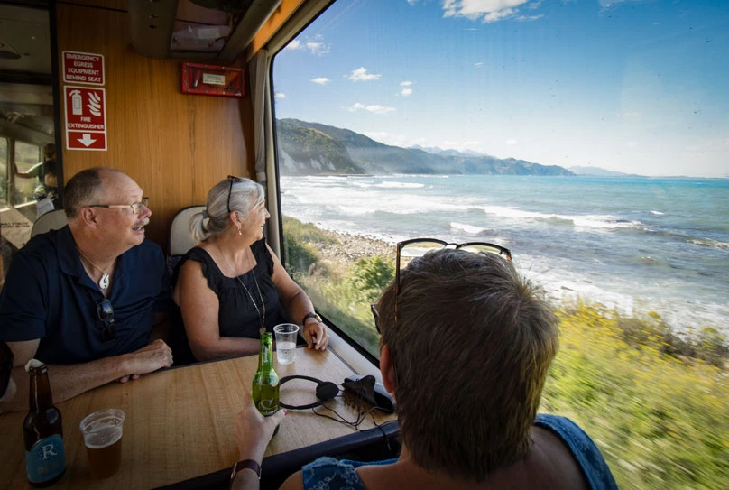 trio sitting at a table on the Coastal Pacific train looking at the view