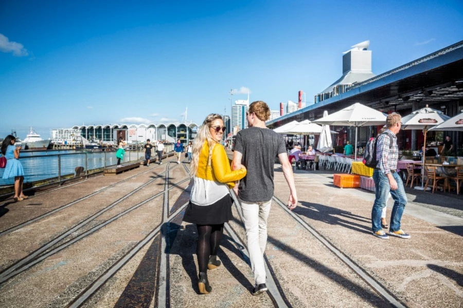 Couple walking down Wynyard Crossing along the waterfront in Auckland central