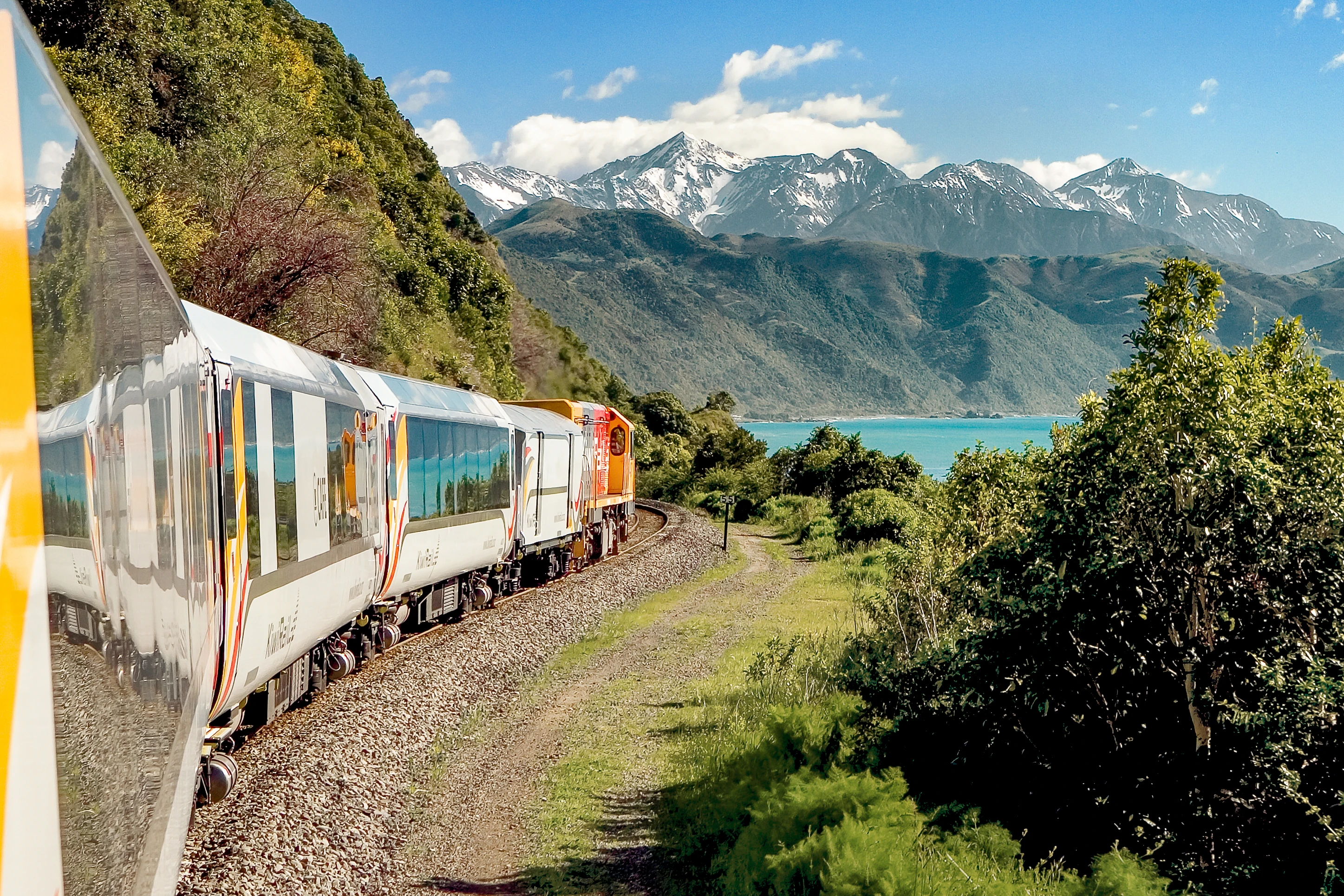 Coastal pacific train travelling through mountains and along the shoreline