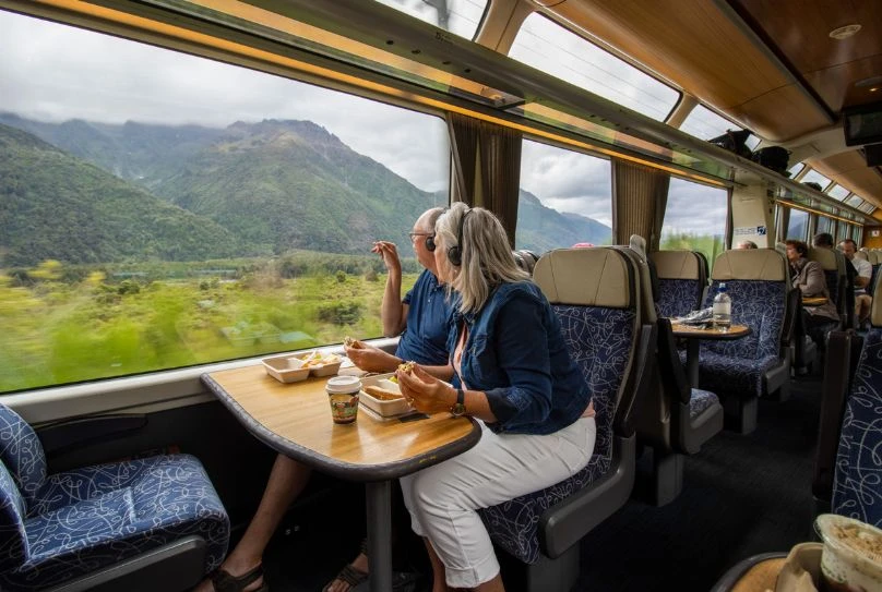 Couple enjoying lunch on the TranzAlpine train amidst stunning West Coast scenery