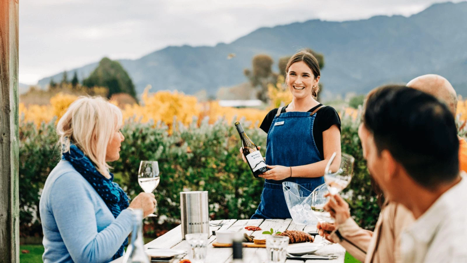 group enjoying a vineyard lunch with wine served in Marlborough