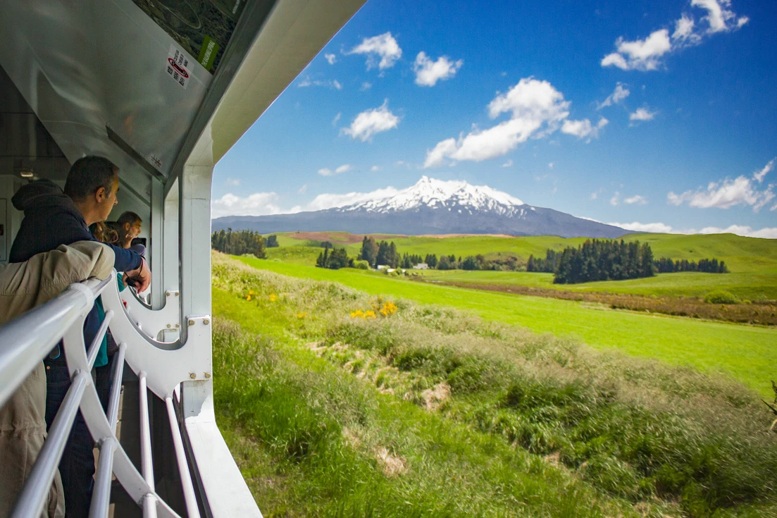 People in the open-air viewing carraige on the Northern Explorer approaching Ruapehu