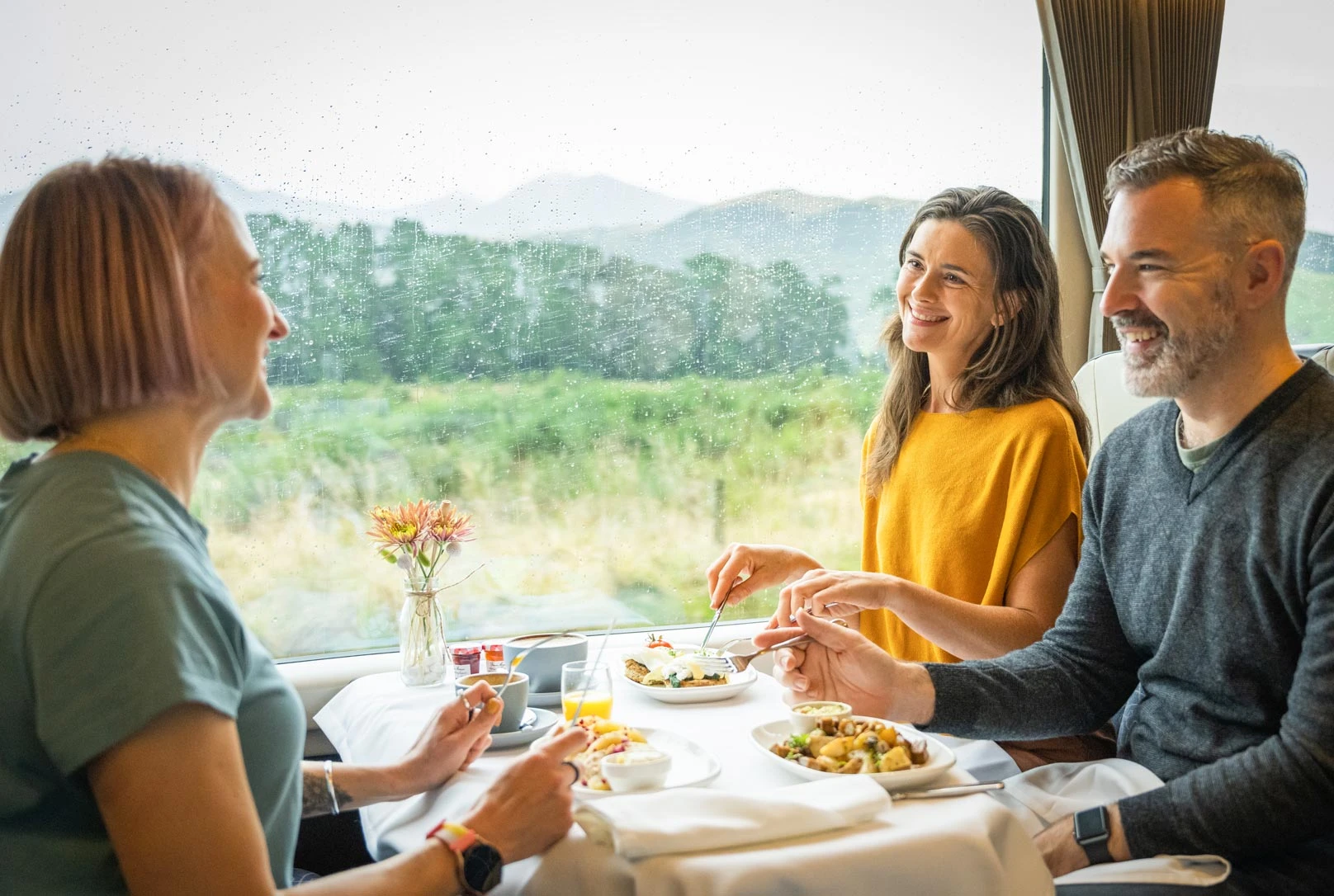 Three people enjoying breakfast aboard the Scenic Plus train carriage